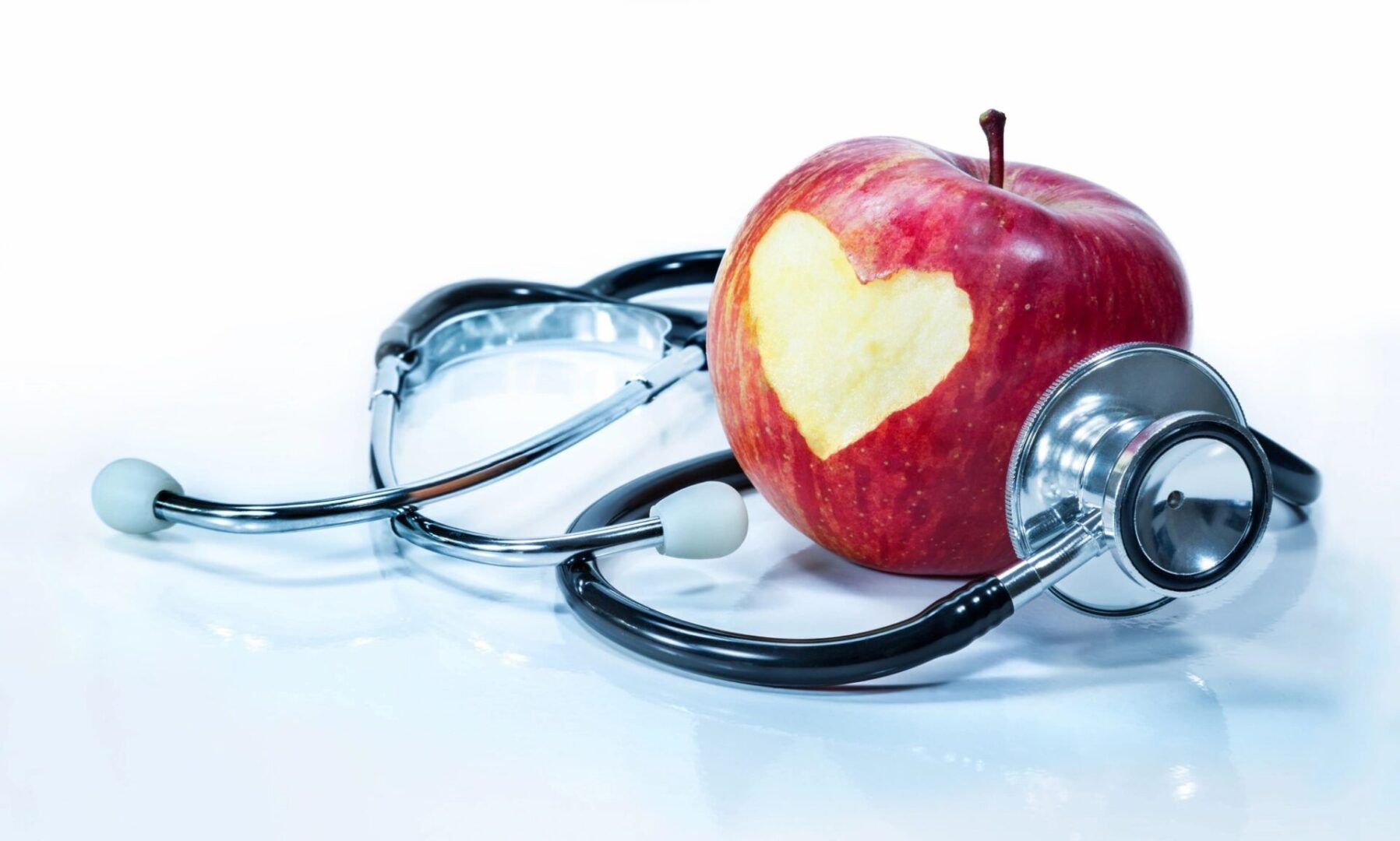 A stethoscope is laying on top of an apple.