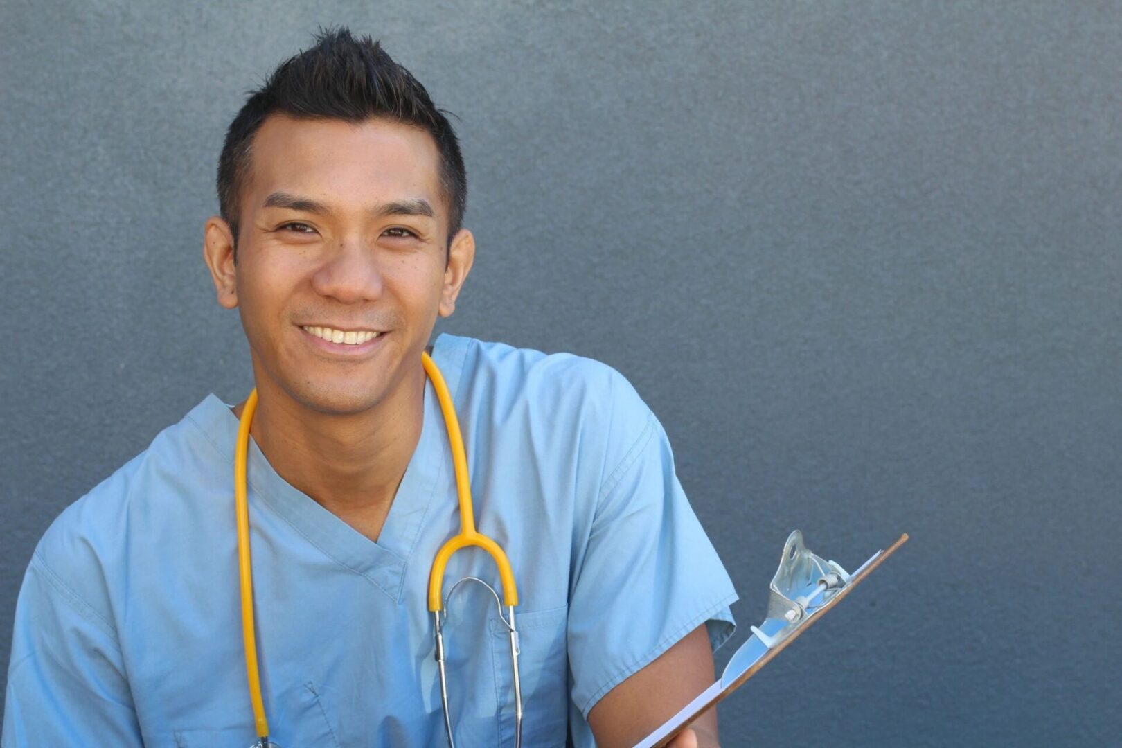 A male nurse holding a clipboard and smiling.