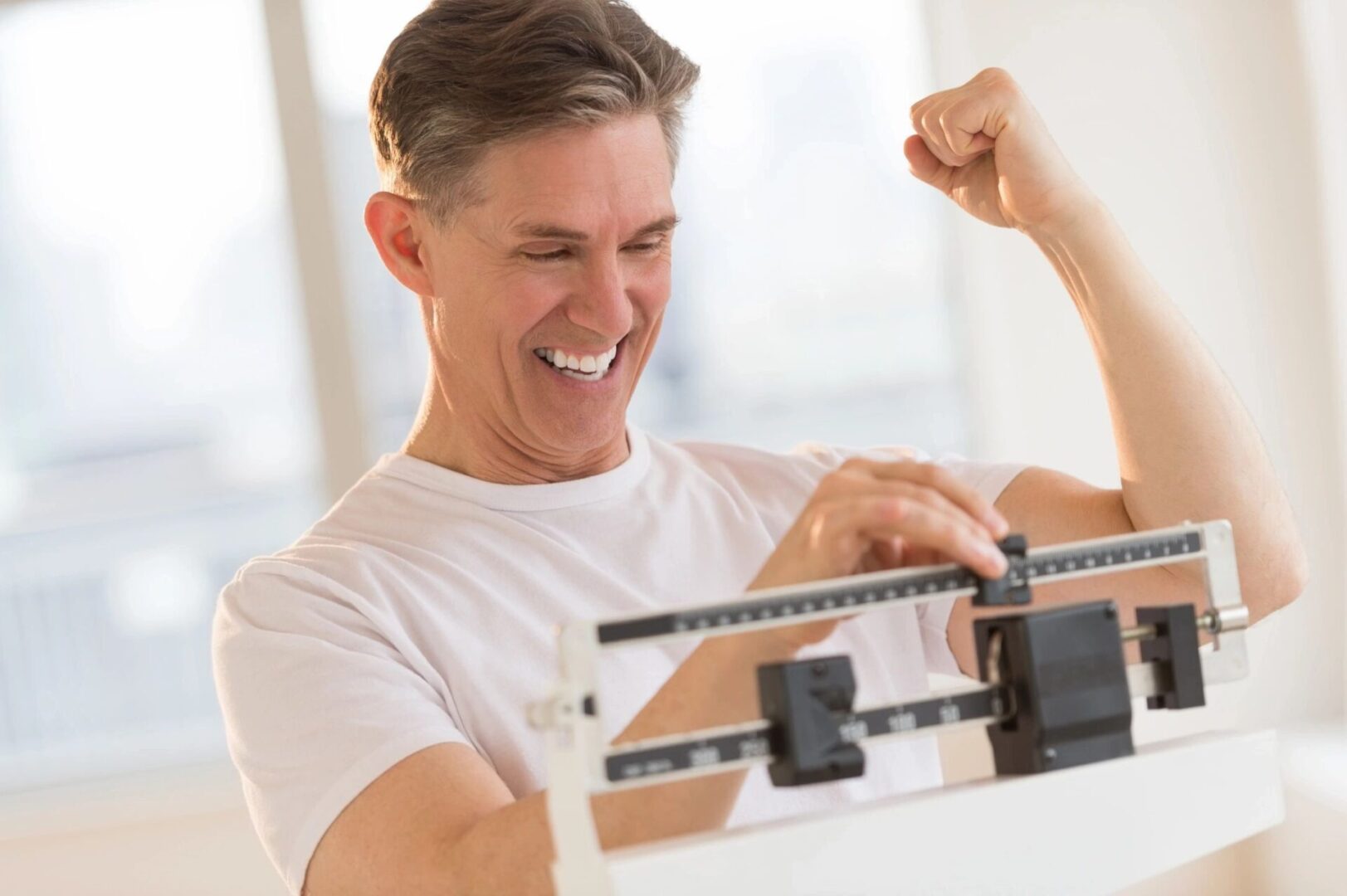 A man is standing on the scale and smiling.